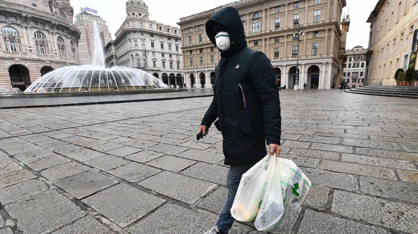 Genoa (Italy), 12/03/2020.- A person wearing a face mask and carrying bags walks in downtown in Genoa, northern Italy, 12 March 2020, during a national lockdown over the novel coronavirus crisis. Tougher lockdown measures kicked-in in Italy on the day after Italian Premier Conte announced the day earlier that all non-essential shops should close as part of the effort to contain the coronavirus. All of Italy is on lockdown until 03 April due to the novel coronavirus crisis. (Italia, Génova) EFE/EPA/LUCA ZENNARO