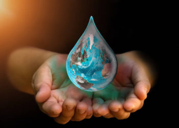 Blue Earth world with dripping water on two hand at wait on abstract black background. Water shortage and earth day concept or world water day. Elements of this image furnished by NASA.