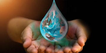 Blue Earth world with dripping water on two hand at wait on abstract black background. Water shortage and earth day concept or world water day. Elements of this image furnished by NASA.
