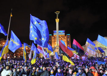 People shout slogans and wave Ukrainian and European Union flags during an opposition rally at Independence Square in Kiev on December 2, 2013. Tens of thousands have been protesting in Kiev, occupying City Hall and blocking entrances to the government headquarters, in an ongoing standoff after the government failed to sign a key EU pact. AFP PHOTO / GENYA SAVILOV        (Photo credit should read GENYA SAVILOV/AFP via Getty Images)