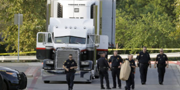 San Antonio police officers investigate the scene where eight people were found dead in a tractor-trailer loaded with at least 30 others outside a Walmart store in stifling summer heat in what police are calling a horrific human trafficking case, Sunday, July 23, 2017, in San Antonio. (AP Photo/Eric Gay)