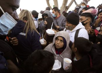 FILE - Asylum seekers receive food as they wait for news of policy changes at the border, Friday, Feb. 19, 2021, in Tijuana, Mexico. The Biden administration hopes to relieve the strain of thousands of unaccompanied children coming to the southern border by terminating a 2018 Trump-era order that discouraged potential family sponsors from coming forward to house the children. (AP Photo/Gregory Bull)