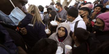 FILE - Asylum seekers receive food as they wait for news of policy changes at the border, Friday, Feb. 19, 2021, in Tijuana, Mexico. The Biden administration hopes to relieve the strain of thousands of unaccompanied children coming to the southern border by terminating a 2018 Trump-era order that discouraged potential family sponsors from coming forward to house the children. (AP Photo/Gregory Bull)