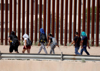 EL PASO, TEXAS - SEPTEMBER 21: Migrants walk along the U.S. border fence to turn themselves in to the U.S. Border Patrol after crossing the Rio Grande from Mexico on September 21, 2022 in El Paso, Texas. In recent weeks, Venezuelans have arrived in increasing numbers in El Paso. The city has had to scramble to find housing and other aid for the migrants.  (Photo by Joe Raedle/Getty Images)